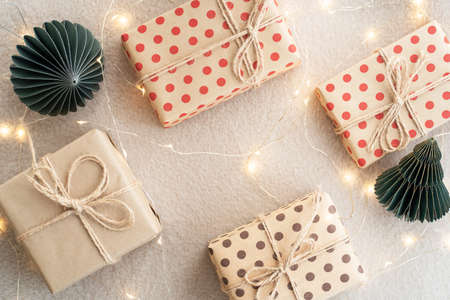 Beige paper gift boxes on a beige carpet lights Christmas garland and Christmas decorations made of...