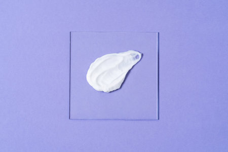 Beautiful smear of cream on glass on a purple background. Cosmetics laboratory research concept....