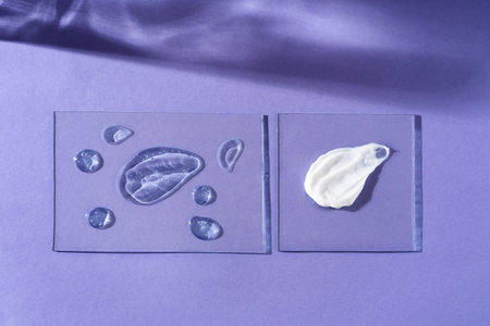 Smears of various skin care cosmetics are spread on glass on a violet background. Cosmetic background.の写真素材
