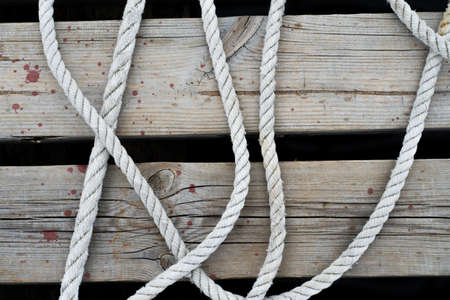 Old worn mooring rope of a yacht on a wooden jetty sea backgroundの写真素材