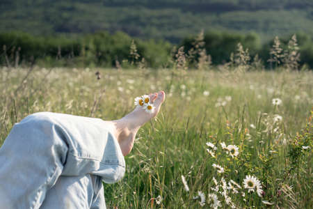 Young girl relaxing lies on a spring flowering meadow. Travel vacation and healthy lifestyle, enjoying nature. freedom and healthy conceptの写真素材