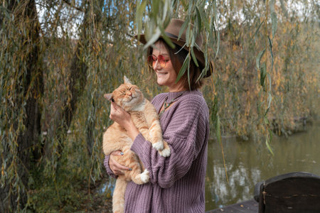 Beautiful young woman is relaxing in nature with her ginger tabby cat. pet conceptの写真素材