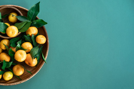 Fresh ripe not perfect small tangerines with leaves lie on a wooden plate. green fruit background. Concept of imperfect productsの写真素材
