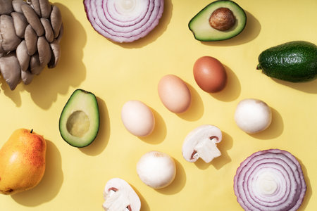 Pattern of champignons and oyster mushrooms, eggs, avocado, purple onion, pear on a yellow...