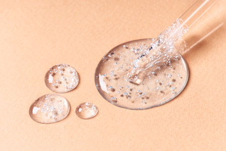 Drops and smears of cosmetics. Drops of liquid transparent gel with bubbles on a beige backgroundの写真素材