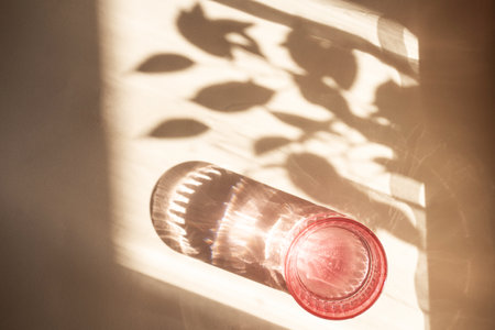 Different glasses for wine, cocktails, drinks, long sun shadow on a light beige background. The...