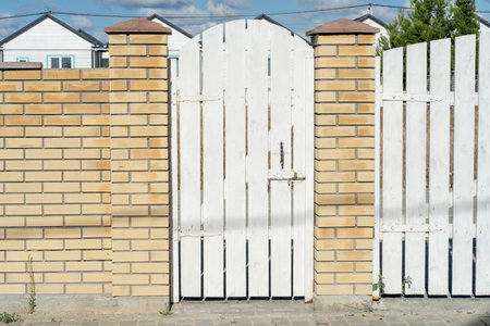 Orange brick stone fence and wooden white gate. natural materials