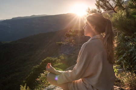 Beautiful young woman with long blonde hair meditates in nature, in a beautiful forest. Travel and a healthy lifestyle, enjoying freedom and natureの写真素材