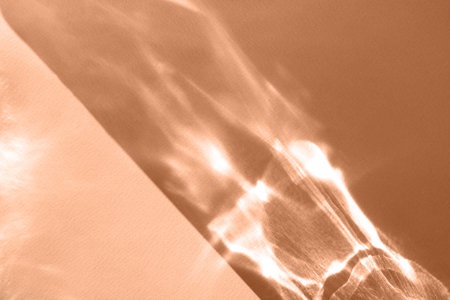 Abstract shadow sun glare from glass, empty background composition for product presentation. Beautiful trendy peach fuzz color background.の写真素材