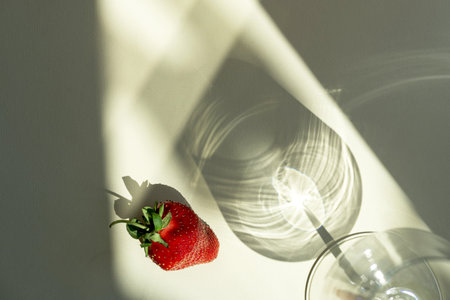 A strawberry and wine glass on a light beige background.の写真素材