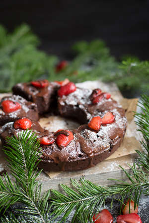 Chocolate cake decorated with strawberries. Brownie. Cake in the shape of a ring, wooden background. Rustic. Food style. Yummy. Sweet idea. Christmas dessert. Christmas tree ornaments. New Year.の写真素材