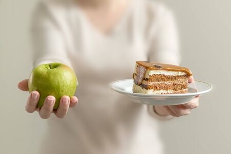 a piece of cake and an Apple in the hands of a young womanの写真素材