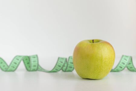 an Apple and measuring tape on a white backgroundの写真素材