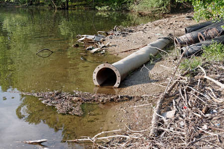 Large pipes running into the lake damaging the environmentの写真素材