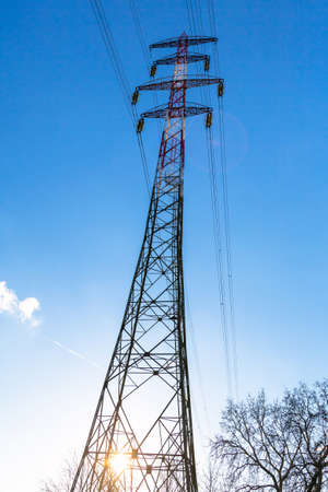 Electric power lines and pylon against blue skyの写真素材
