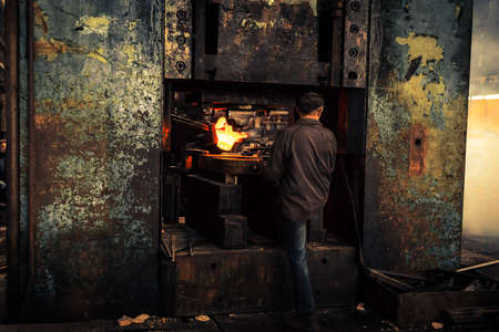 Hot iron in smeltery held by a workerの写真素材