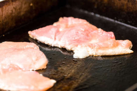 cooking meat in a frying pan closeupの写真素材