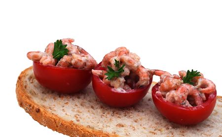 Three cocktail tomatoes with shrimps and parsley on a slice of bread, on white, shallow dofの写真素材