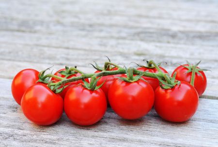 Cluster of cocktail tomatoes on teak woodの写真素材