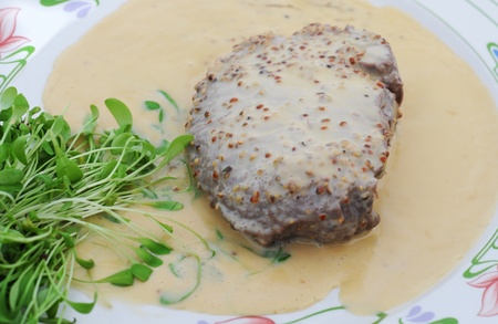 steak with pepper cream sauce and cress on decorated plateの写真素材