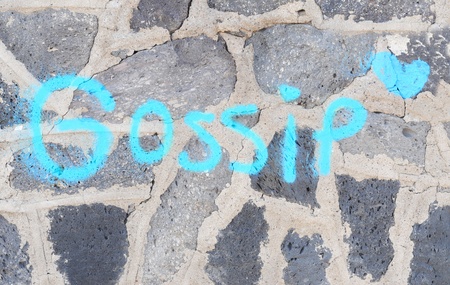 The word gossip in blue graffiti on grey volcanic wallの写真素材