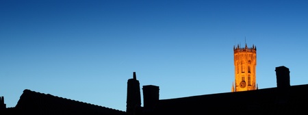 bruges by night with dark chimney silhouettes and belfry with artificial lightingの写真素材