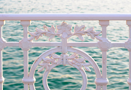 weathered wrought iron fence with flower pattern in front of the sea, selective focusの写真素材