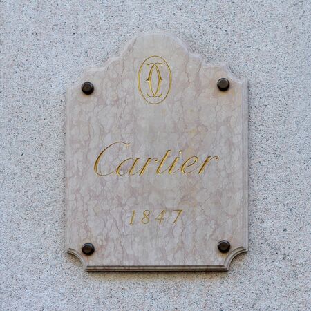 MILAN, ITALY - MARCH 3, 2016: Cartier, French jeweler since 1847, currently owned by the Compagnie Financiere Richemont SA. Golden name and logo on pink marble plaquette in Via Monte Napoleoneのeditorial素材