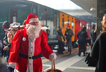 MILAN, ITALY - DECEMBER 17, 2016: Father Christmas welcomes people at station Porta Garibaldi with colorful vintage train in the backgroundのeditorial素材