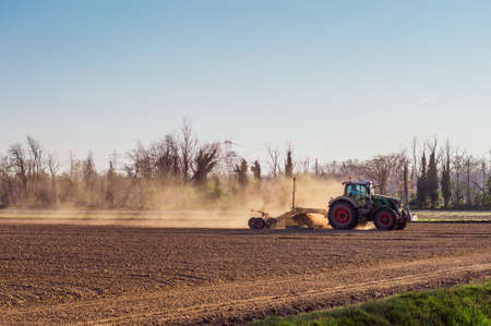 Tractor working in the field, preparing the land for planting, working plowed fieldの写真素材