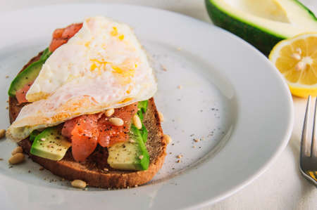 Fresh toast with rye bread,avocado,salmon,seeds and egg on a plate.Vegetarian food.の写真素材