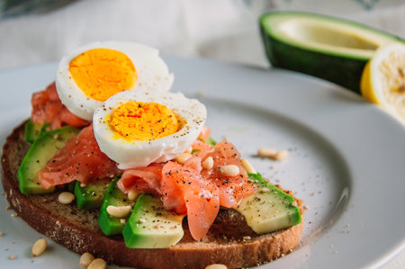Fresh toast with rye bread,avocado,salmon,seeds and egg on a plate.Vegetarian food.の写真素材