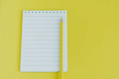 Top view image of an open notebook with blank pages and pencil. school notebook on yellow background, spiral notepad tableの写真素材
