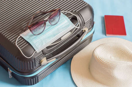 Flat lay composition with suitcase, protective mask,hat,glasses,passport, space for text. Travel conceptの写真素材