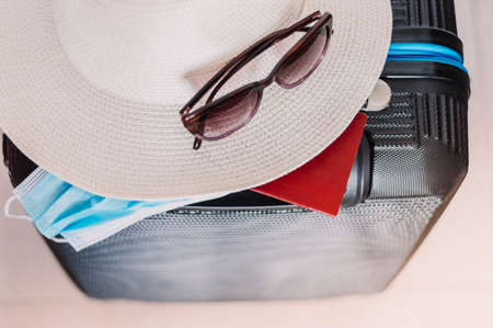Flat lay composition with suitcase, protective mask,hat,glasses,passport, space for text. Travel conceptの写真素材