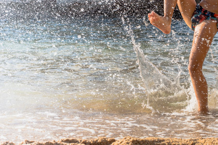 happy boy is playing splashes in the water on the beach.lifestyleの写真素材