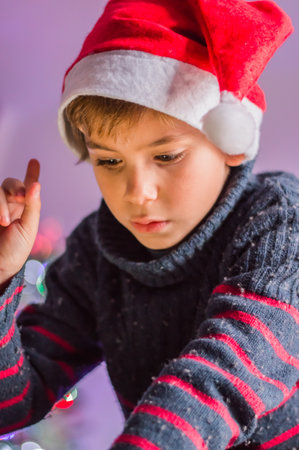 A happy child in Santa Claus's hat thinks about a gift and plaing.の写真素材