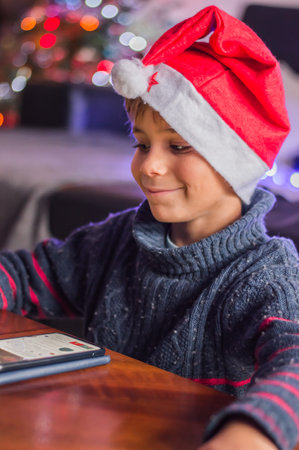 A happy child in Santa Claus's hat thinks about a gift and plaing.の写真素材