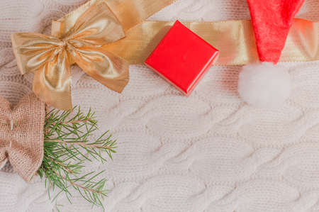 Santa Claus hat, Christmas tree branch and decorations over light knitted background and copy space