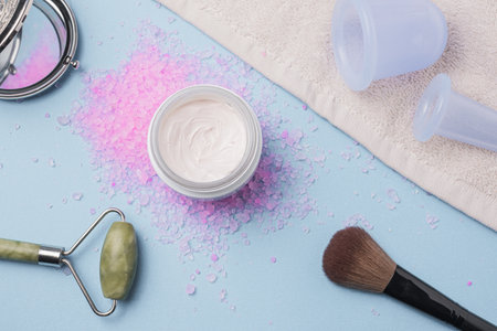 Flatlay with cream, bath rose salt, massage vacuum jars on blu background.Spa and natural skin care conceptの写真素材