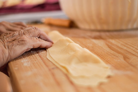 Hands of an old woman preparing ravioli pasta. Close up on wood backgroundの写真素材
