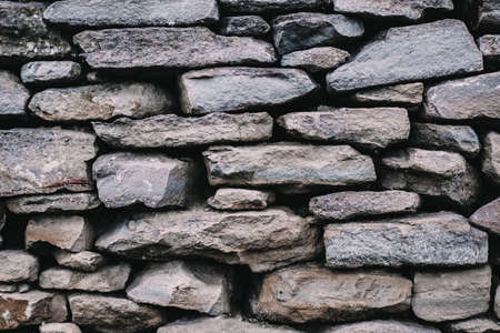 Background of a stone wall closeup. Texture of large and small multi-colored stones in concrete. Old wall.の写真素材