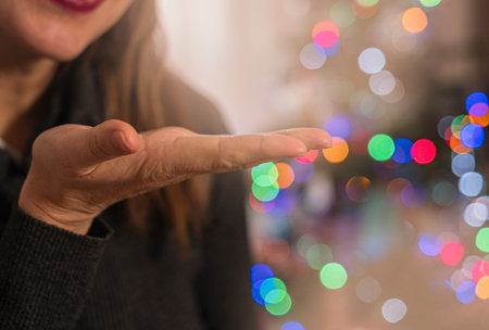 Empty female hand holding palm. Blurred Christmas tree on background. Christmas card with space for textの写真素材