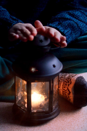 Close up child in festive clothes and Christmas socks sitting next to the chtistmas lantern.の写真素材