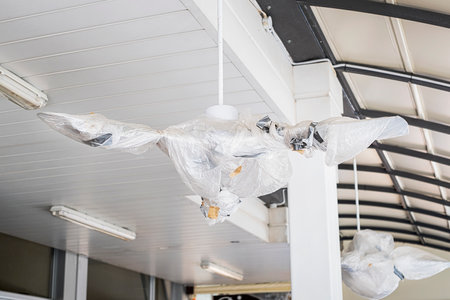 Metal and white ceiling and large fans are covered for open air industry buildingの写真素材