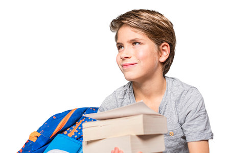 Portrait of schoolboy with school bag and books. Happy teen boy, isolated on white background.の写真素材