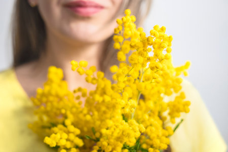 Beautiful young woman with mimosa flowers on white backgroundの写真素材