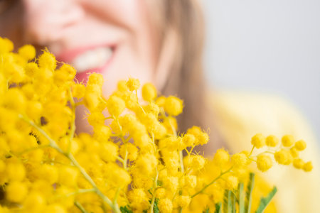 Beautiful young woman with mimosa flowers on white backgroundの写真素材