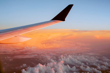 View outside the plane window to the wing and clouds at sunsetの写真素材