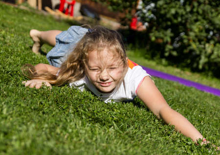 girl lies on a grass and closes her eyes from a sunの写真素材